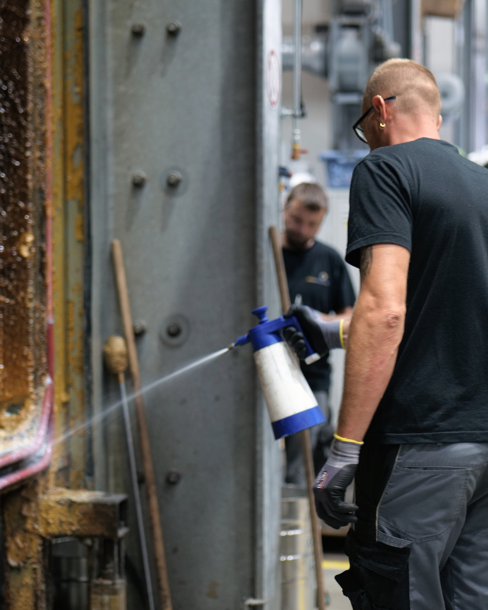 Mann sprüht Flüssigkeit in Werkstatt